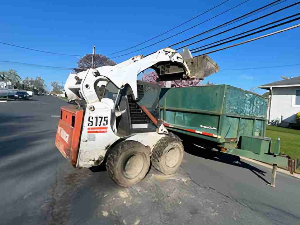 Skid steer loading debris into a roll off container